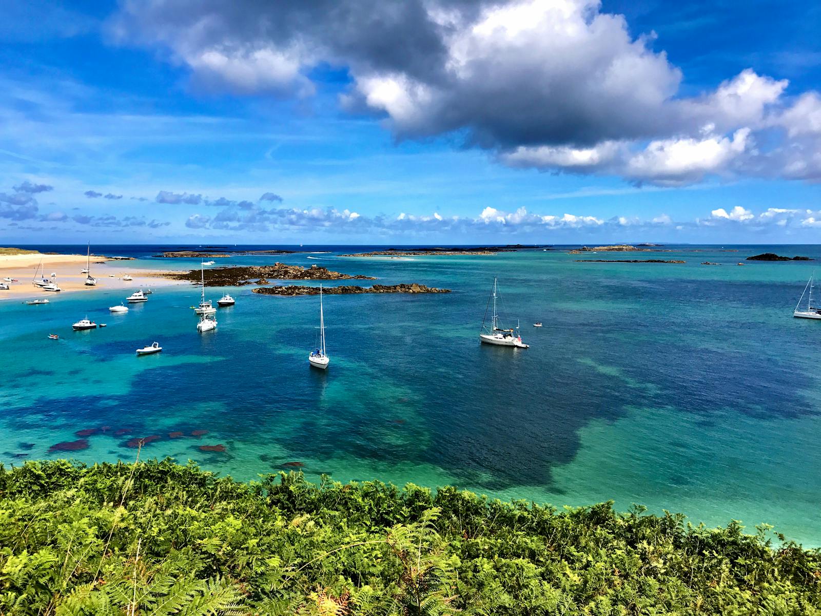 Beautiful seascape of Herm, Guernsey featuring sailboats on clear blue water with a vibrant sky.